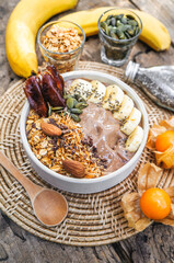 Fototapeta na wymiar Healthy food smoothie bowl Fresh fruit smoothie is good for the body. with chocolate, fruits, nuts, seeds and homemade granola, banana for healthy on a wooden table