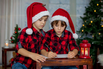 Fototapeta na wymiar Two adorable children, boy brothers, writing letter to Santa