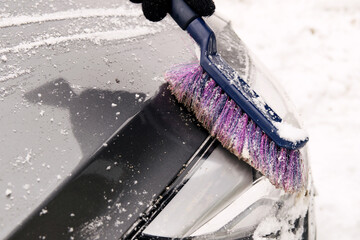 A male driver removes snow from the headlamp with a car brush © Наталья Анюхина