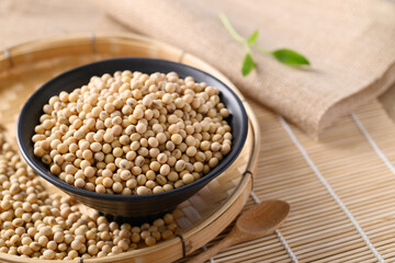 Soybeans seed in a black bowl with spoon on wooden background