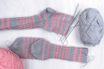 Skeins of thread and knitting on a white wooden background.