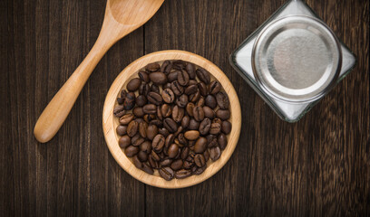 A wooden dish with coffee beans on a wooden table.
