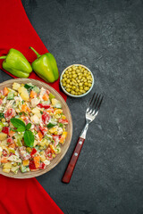 top close view of veggie salad on red napkin and with veggies and fork on side and free place for your text on dark grey background