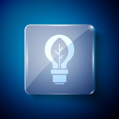 White Light bulb with leaf icon isolated on blue background. Eco energy concept. Alternative energy concept. Square glass panels. Vector.