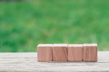 Four empty wooden blocks for own customer text or letters isolated on green nature background, banner copy space