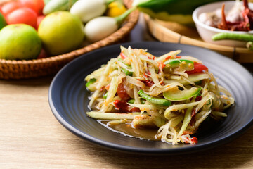 Thai food (Som tum), Spicy green papaya salad with vegetables on wooden table