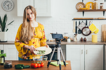 Pregnant girl blogger shoots a video of a salad recipe on a smartphone camera