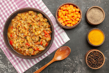 top view roasted eggplant salad in bowl bowls with different spices cuts cubs of carrot on dark background