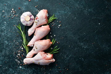Raw chicken drumsticks with rosemary, spices and vegetables. Top view. Free space for your text.