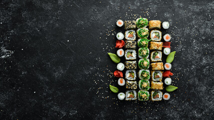 Set of tasty sushi and maki rolls on black stone background. Japanese food. Top view. Free space for your text