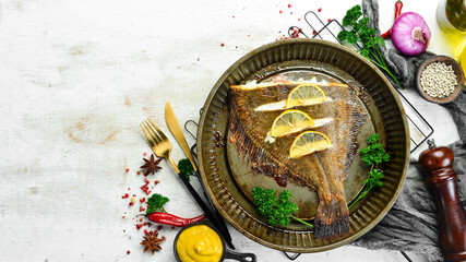 Obraz na płótnie Canvas Baked flounder fish with lemon and spices on a metal baking dish. Seafood. Top view. Free space for text.