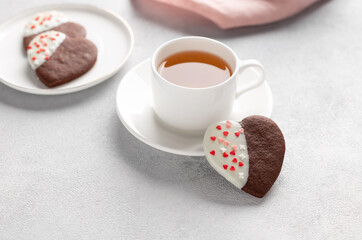 Valentines day greeting card. decorated heart shaped cookies and white cup of tea on gray background. space for text