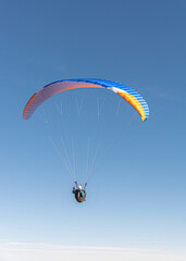 The paraglider is flying in the sky.