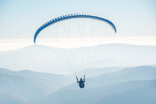 The paraglider is flying in the sky.