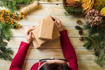 The woman packs Christmas presents from eco materials