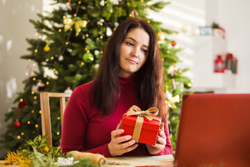 Woman is sitting at the table and unpacking Christmas gift