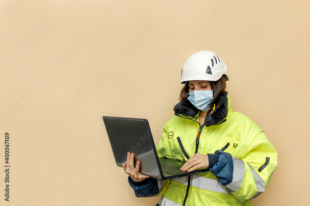 Wall mural female industrial worker in medical mask. woman engineer with white hard hat helmet working on lapto