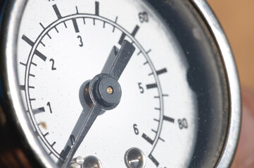 Close-up of an old industrial pressure gauge display with worn protective glass. Macro