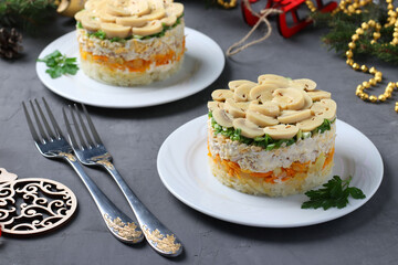 Puff salad with chicken, pickled mushrooms, potatoes and carrots on plates. New Year's composition.