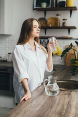 Pregnant girl drinking clean water in the kitchen