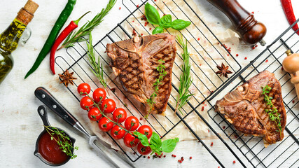 Grilled aged T-bone steak with rosemary on a white wooden background. Top view. Rustic style.