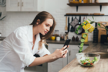 Pregnant girl takes photos of a prepared salad on her smartphone