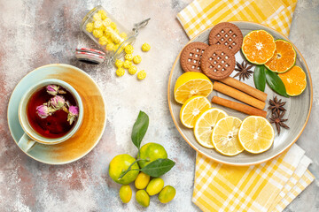 Set table for coffea and tea time with a cup of tea and biscuits and lemon slices on white table