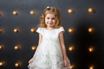 Full length of beautiful little girl in dress standing and posing over white background