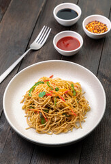stir fried vegetarian noodles with sauce served in a white plate with fork