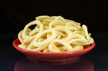 Potato chips onion ring on glass table with reflection