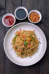 stir fried vegetarian noodles with sauce served in a white plate with fork