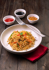 stir fried vegetarian noodles with sauce served in a white plate with fork
