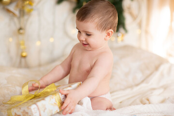 Fototapeta premium Happy Baby In A Christmas Hat With A Gift