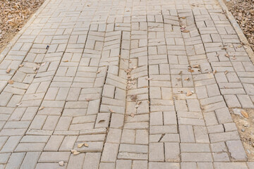 The paving slabs are broken. Uneven sidewalk. Poor quality sidewalk. Curved paving slabs. Curved road in the city