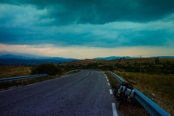 Scenic landscape with  Pirin mountain range, outgoing road with lonely bicycle and thunder clouds background. Bulgaria.