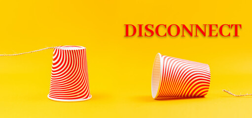 Two cardboard red cups with strings lying apart. Children's homemade toy walkie-talkie. Yellow background. Banner. The concept of communication interruption and disconnection