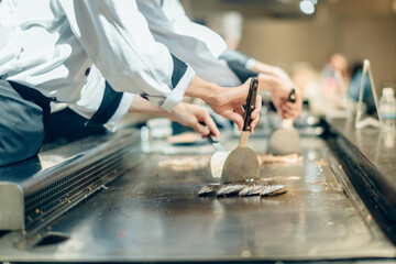 Hand of man take cooking of meat with vegetable grill, Chef cooking wagyu beef in Japanese teppanyaki restaurant