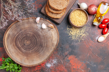 Horizontal view of dinner background wooden cutting board greens spoon garlic and tomato on dark background