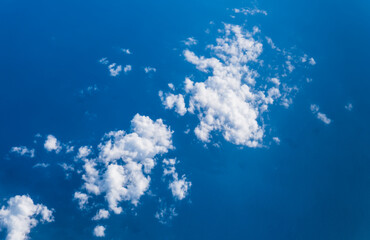 Fototapeta na wymiar White clouds taken from the airplane against the blue ocean underneath.