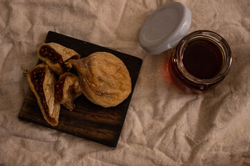 dried figs on wooden dish and fig juice in glass jar with dark background. Space for text. backlight
