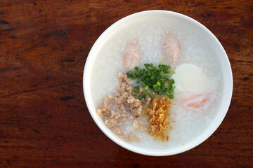 Top view Rice porridge or Minced Pork Congee with Soft Boiled Egg in bowl on wood brown table - favorite Breakfast in Asia - Morning food 