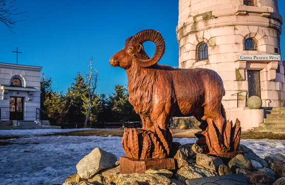 Wielka Sowa Mount,Poland - March 22, 2019: Large wooden statue of mouflon next to lookout tower on the peak of Wielka Sowa Mountain in Owl Mountains Landscape Park, Poland