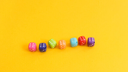 Small dice of various colors on yellow background.