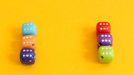 Small dice of various colors on yellow background.