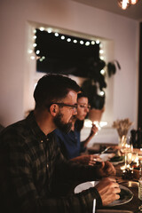 Young man having dinner with friends around a candlelit table