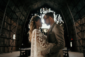 young couple about to kiss in a barn on wedding day © Olivia