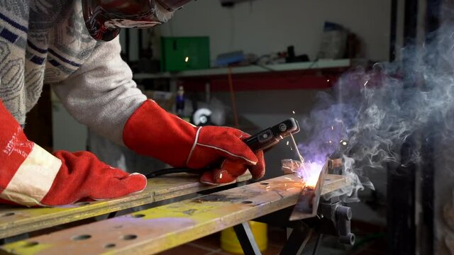 Man welding a metal joint with a soldering iron giving off a lot of smoke and sparks. slow motion smoke. sparks in slow motion. slow motion welder