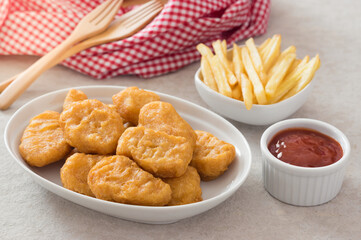 Chicken nuggets with potatoes chips and ketchup sauce.