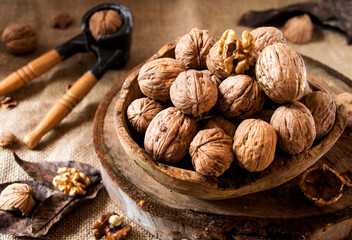 olivenholzschüssel mit walnüssen auf einer baumscheibe mit nussknacker