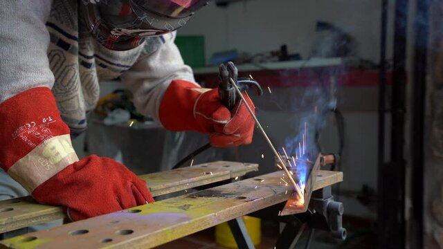 Man with gloves and mask welding a metal joint in his workshop. metal welding in a workshop.